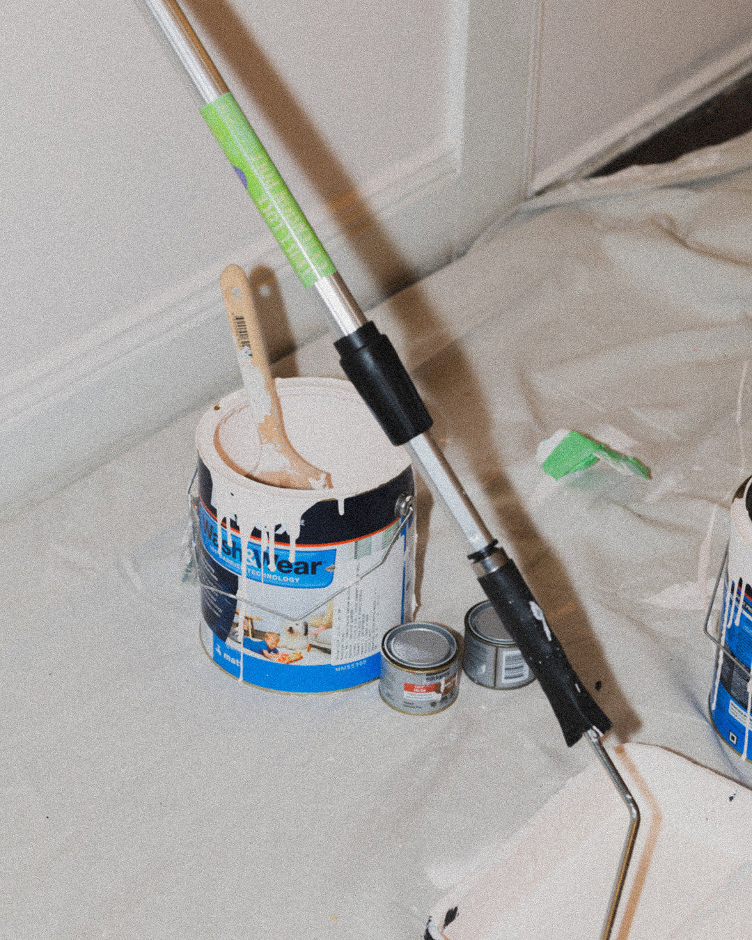 Paint bucket and roller brush resting in a tray. 